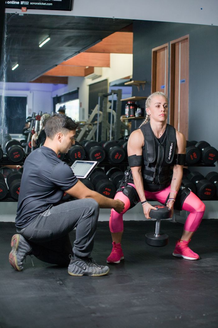 Woman in a personal training session using weights indoors, showcasing strength and fitness.