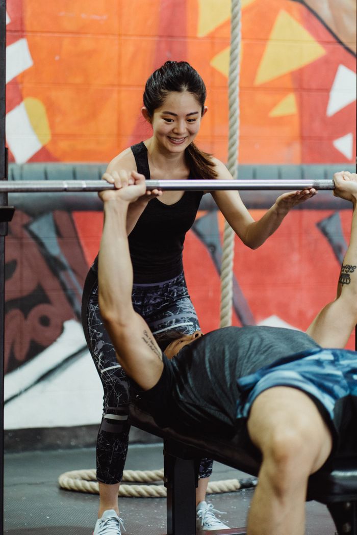 A couple engaged in a workout session featuring bench press exercises in a vibrant gym setting.