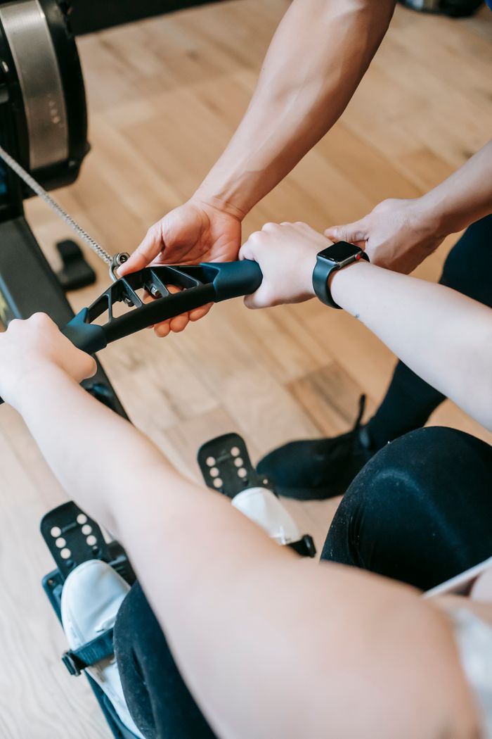 Mastering the First Impression: Your intriguing post title goes here High angle of crop anonymous trainer assisting woman exercising on rowing machine in sports club